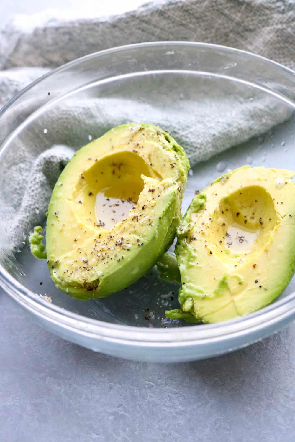 sliced and peeled avocados in glass bowl