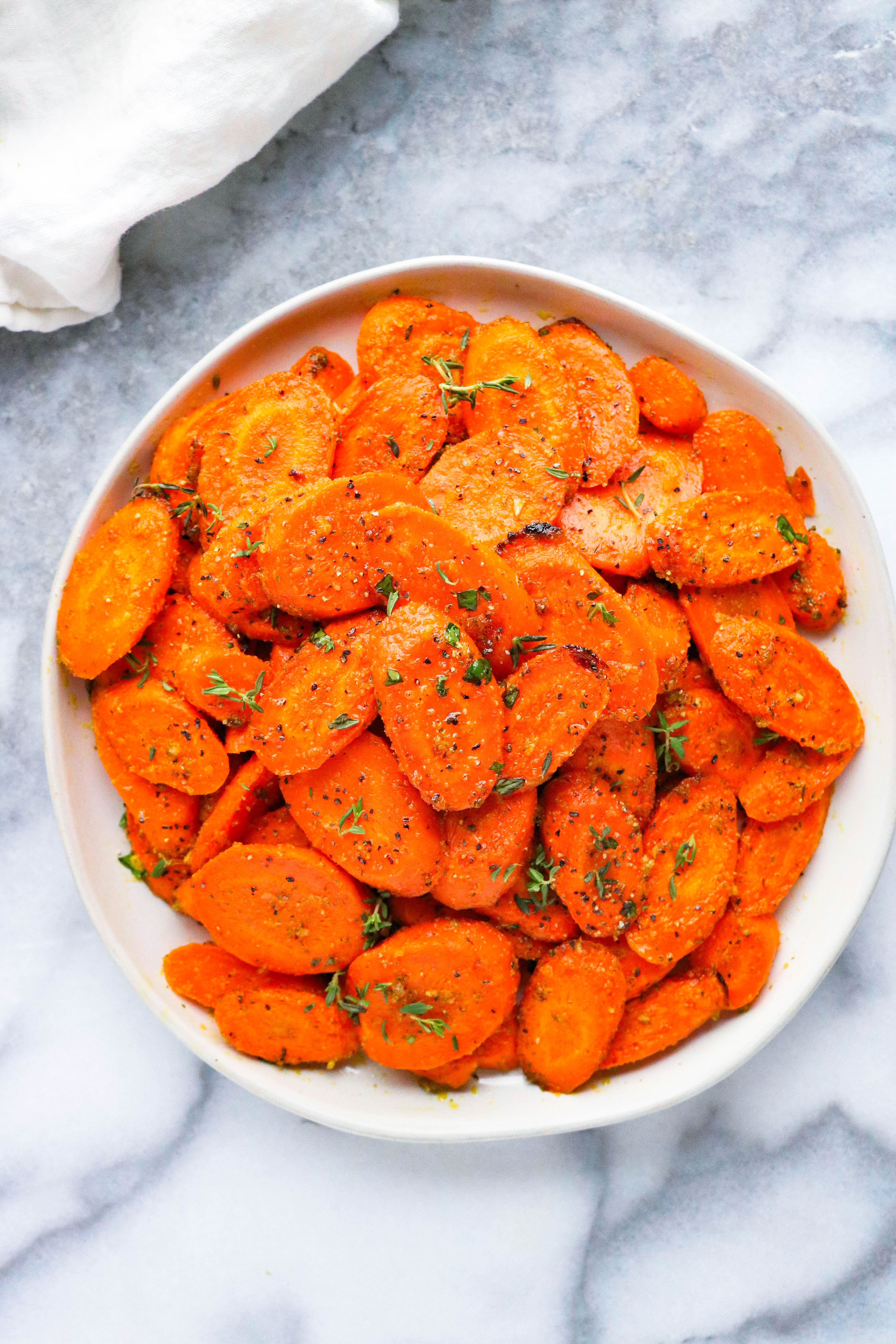 White bowl with easy ranch roasted carrots topped with fresh herbs