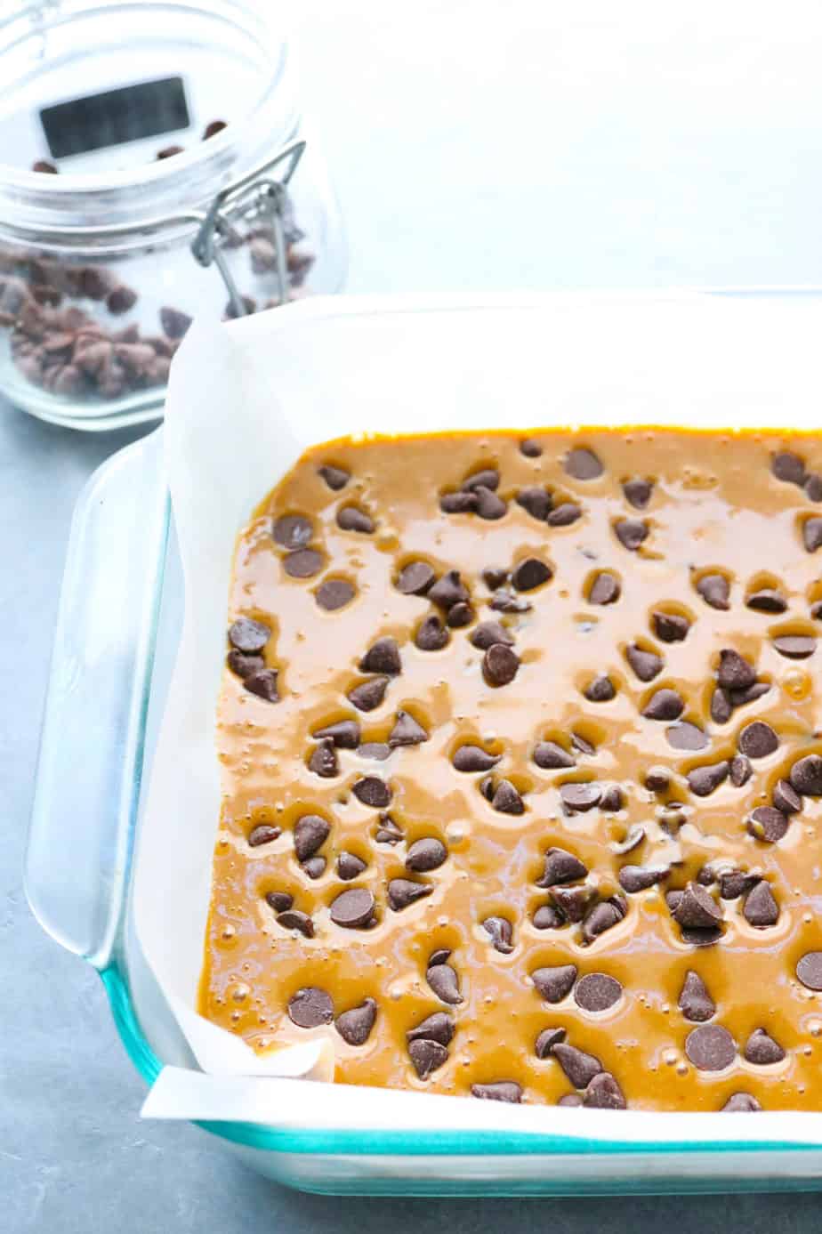 Chocolate chip blondie batter spread in a baking dish with chocolate chips