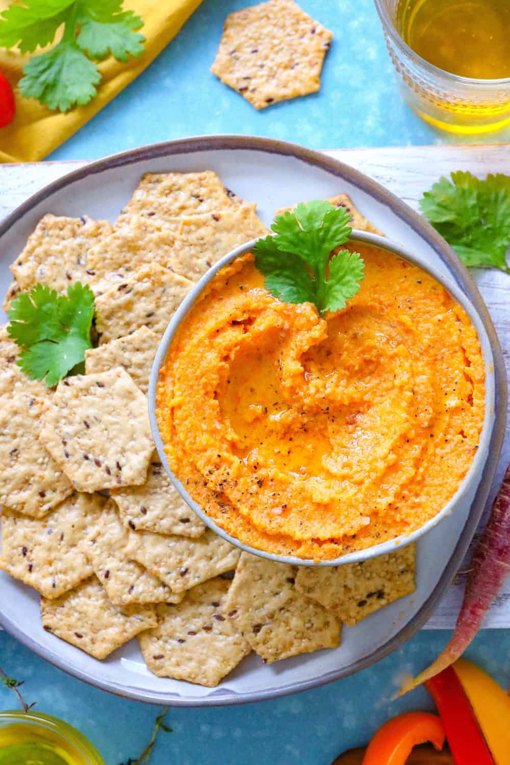 orange-veggie-dip-in-a-gray-round-bowl-on-a-plate-with crackers and vegetables