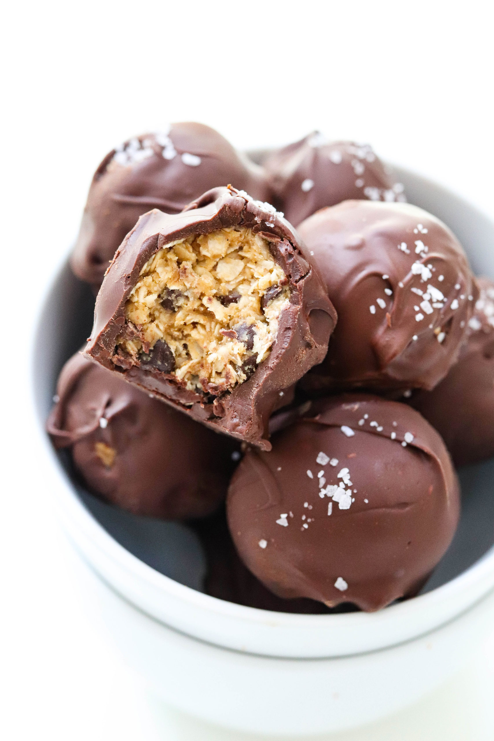Chocolate covered energy bites with sea salt on top in a round white bowl