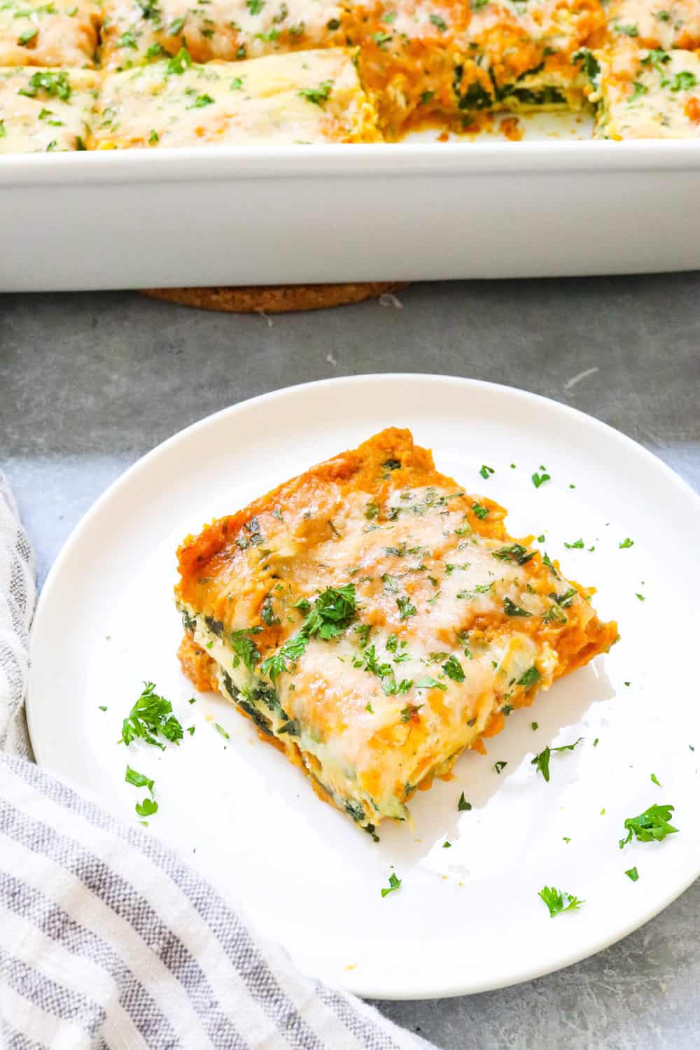Slice of spinach lasagna on a white plate