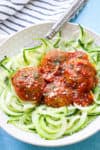 vegan meatballs in a bowl on top of zucchini noodles with tomato sauce