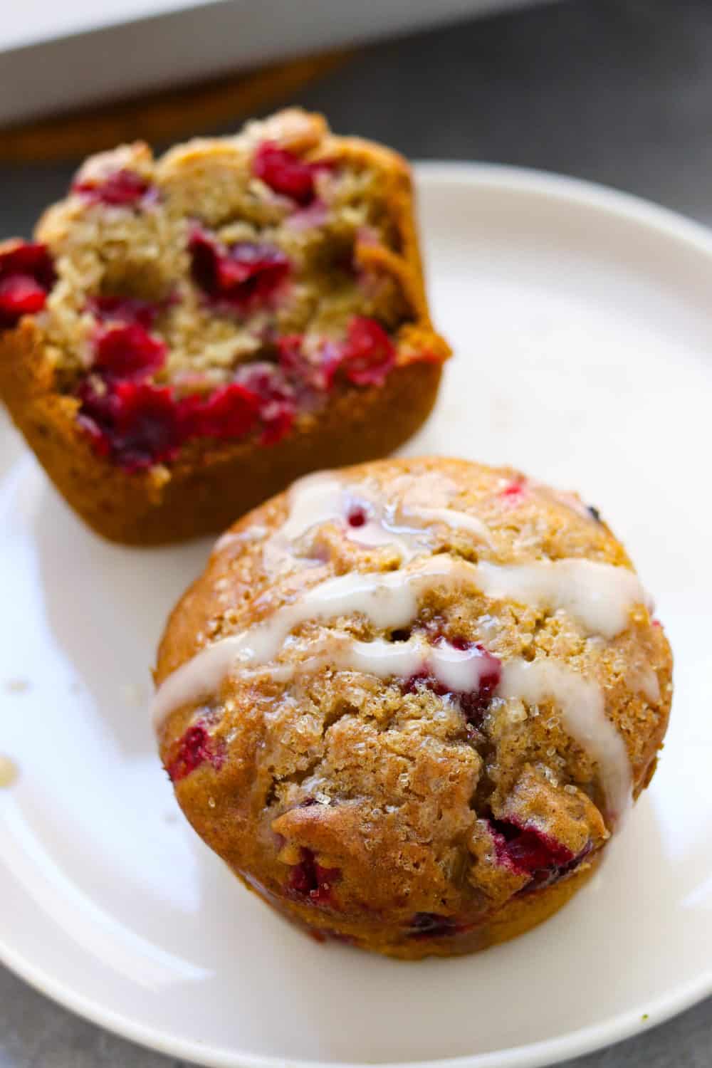 cranberry orange muffin with glaze on it on top of a white round plate