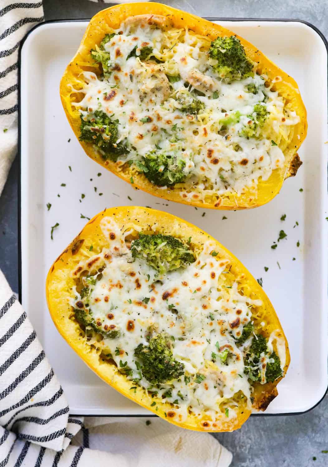 two baked spaghetti squash filling with broccoli and melted cheese on a baking sheet