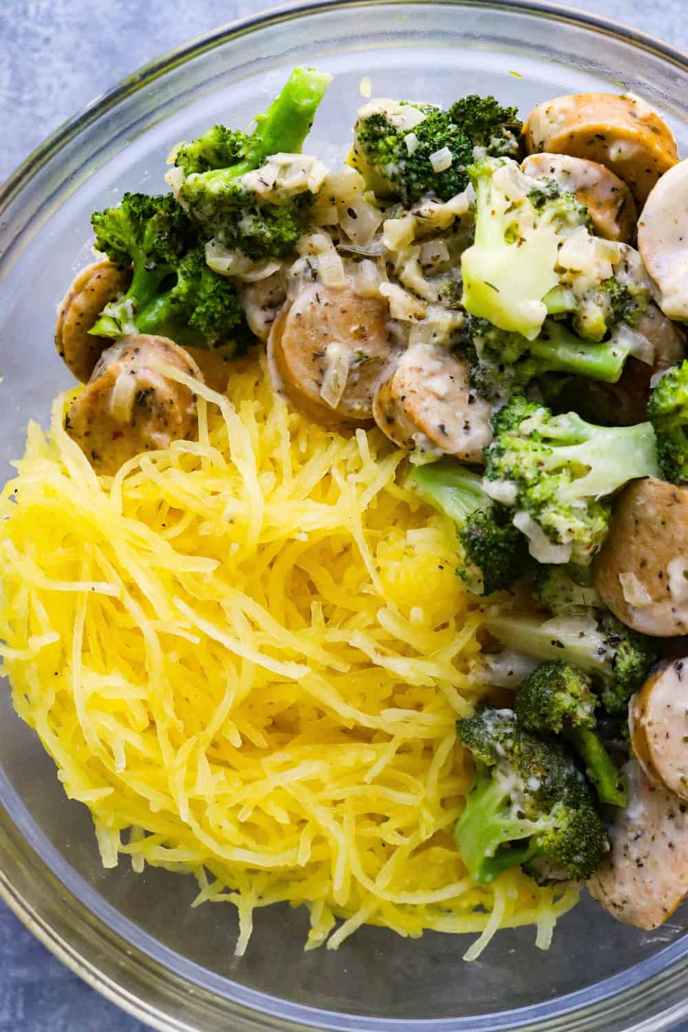 squash strands with creamy broccoli and sausage mixture in a round glass bowl 