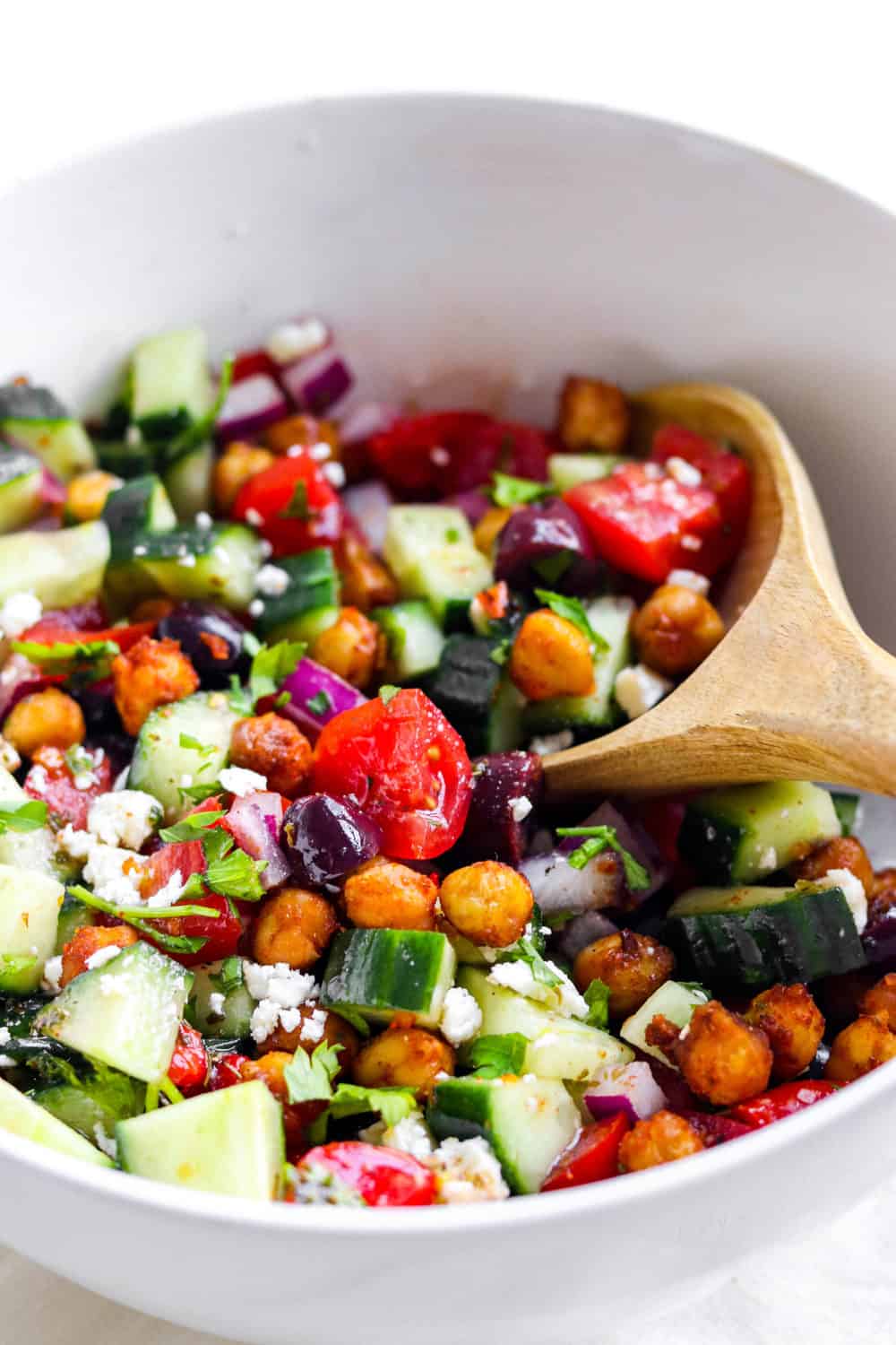 round white bowl filled with chopped veggies, olives and roasted Mediterranean chickpeas