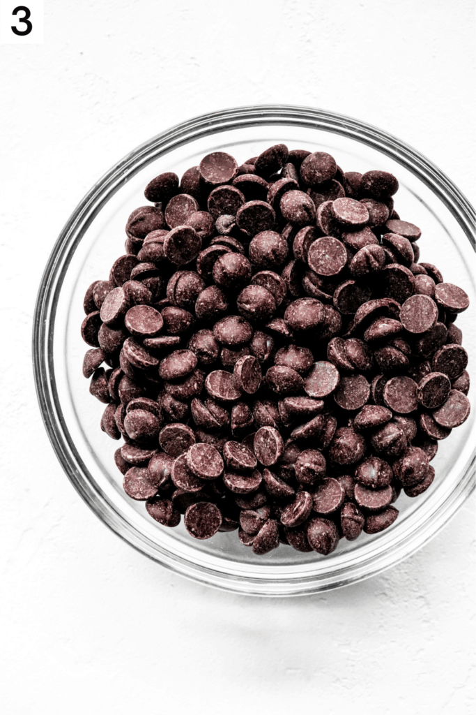 Round glass bowl filled with dark chocolate chips. 