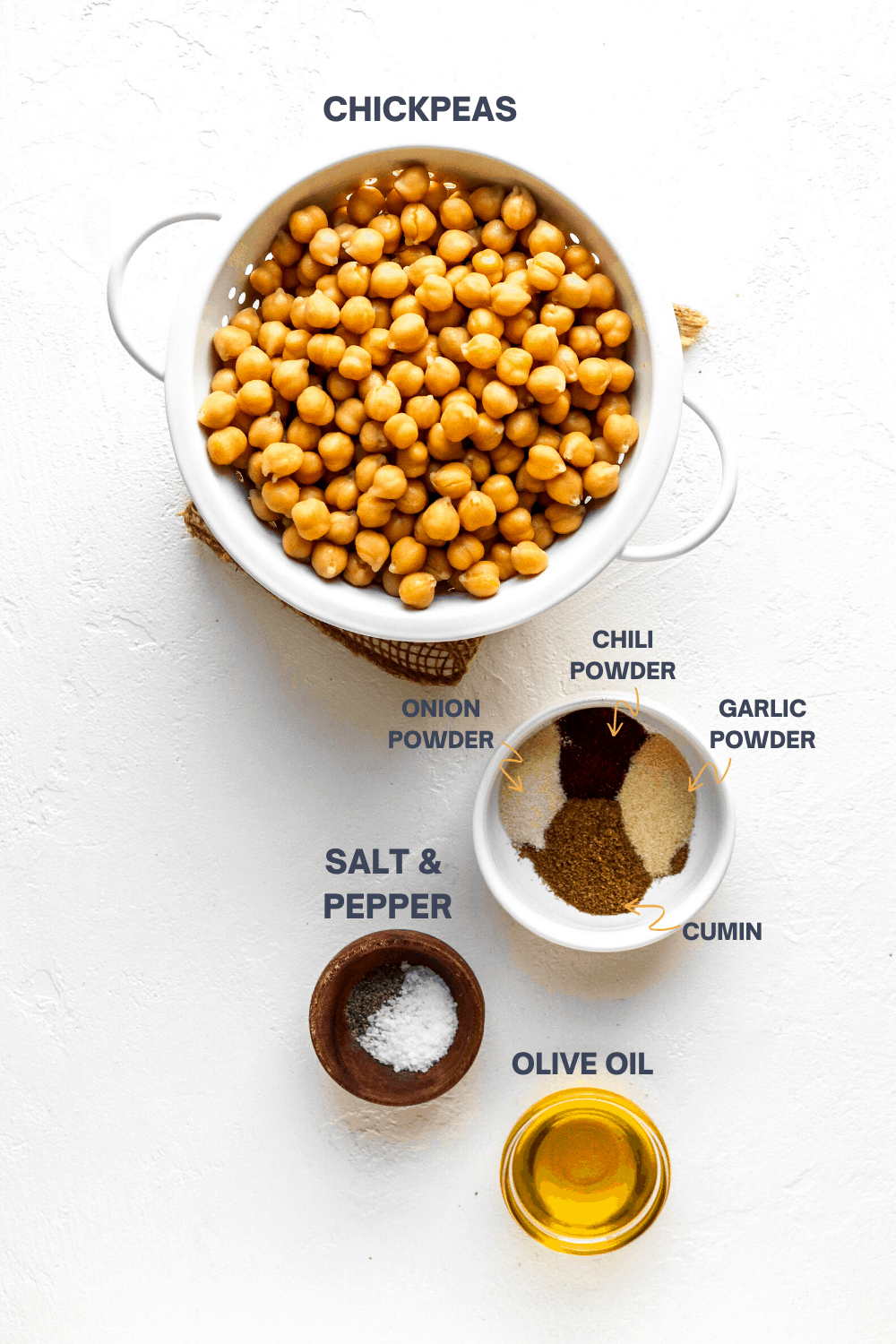 Beans in a white strainer with a bowl of spices, olives oil and salt and pepper on a white surface.