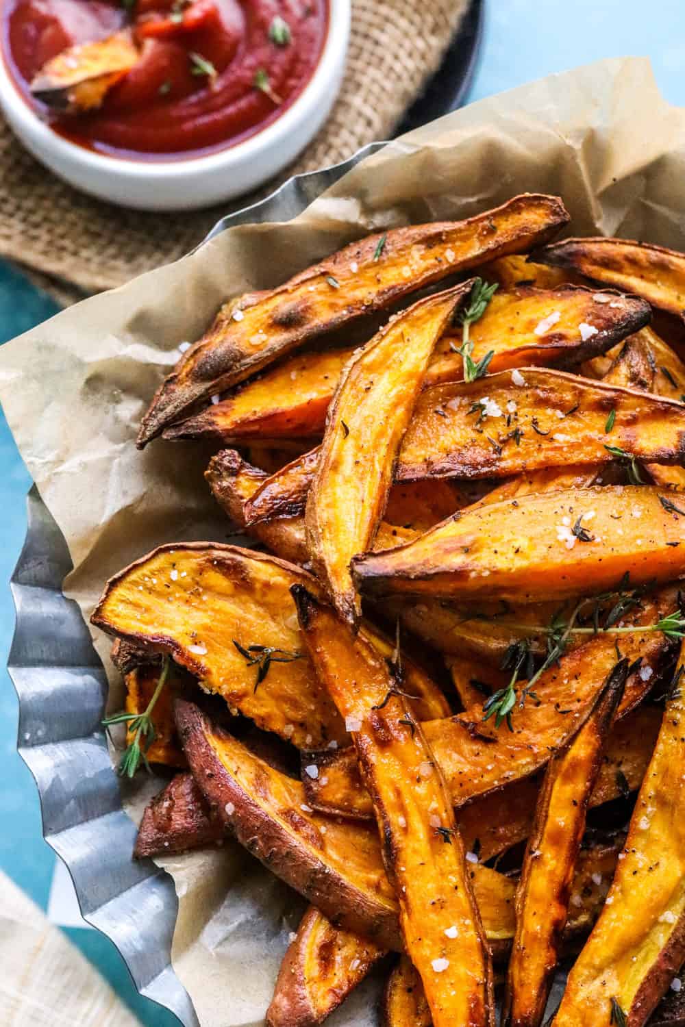 Golden brown sweet potato wedges in a basket on top of brown paper