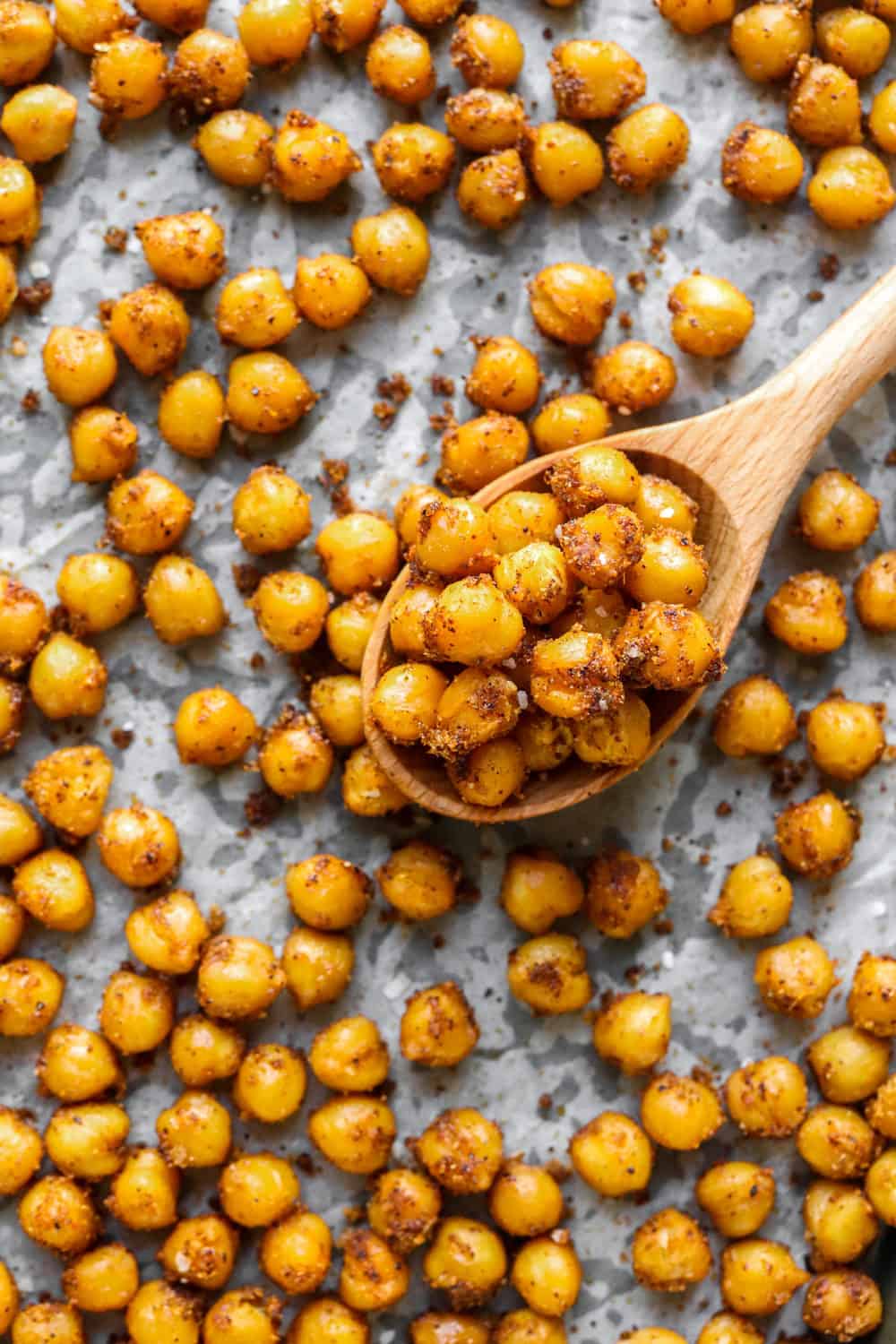 Chickpeas on a sheet pan with a wooden spoon on it
