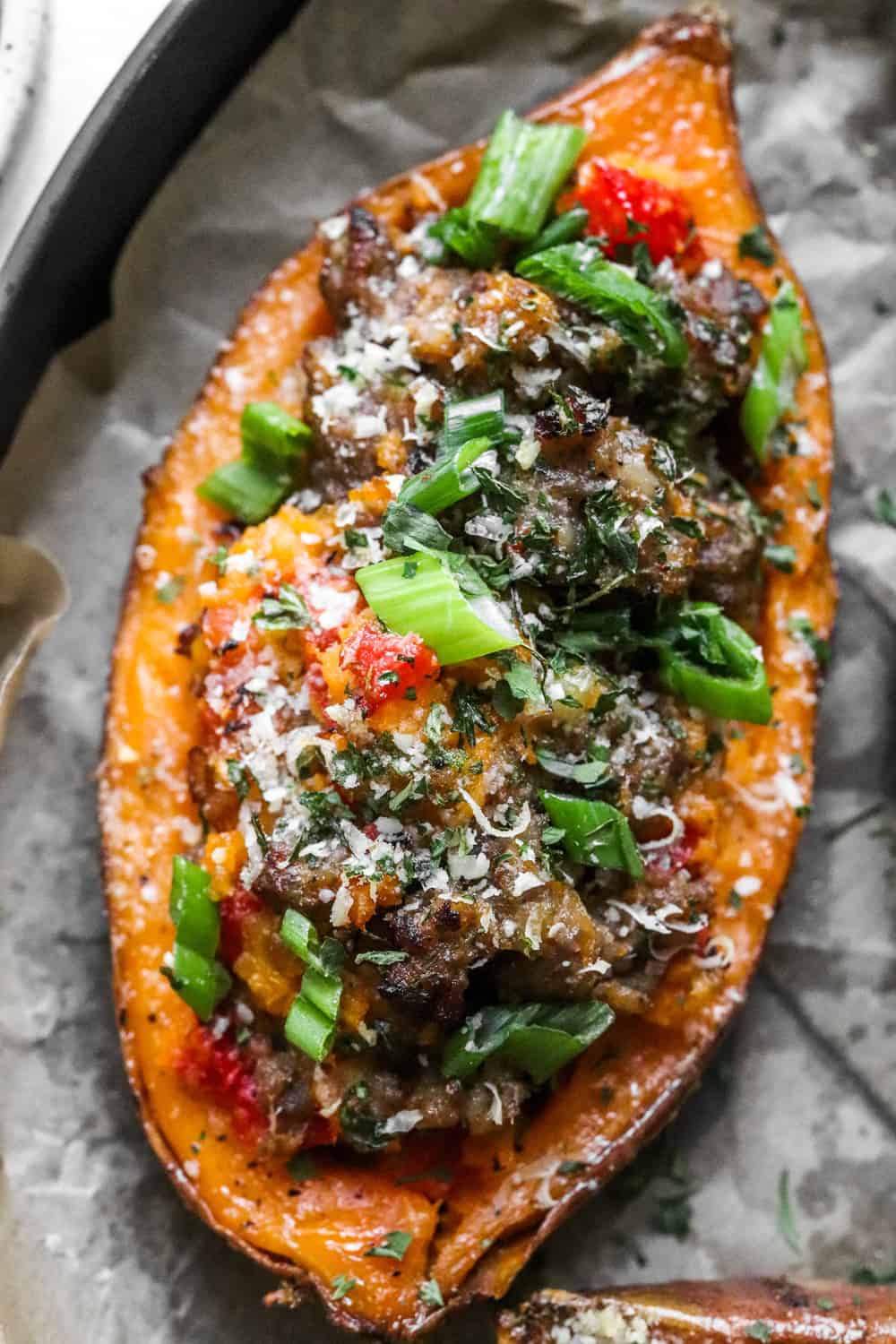 One twice baked sweet potato filled with cooked sausage and peppers topped with parmesan cheese and green onion. 