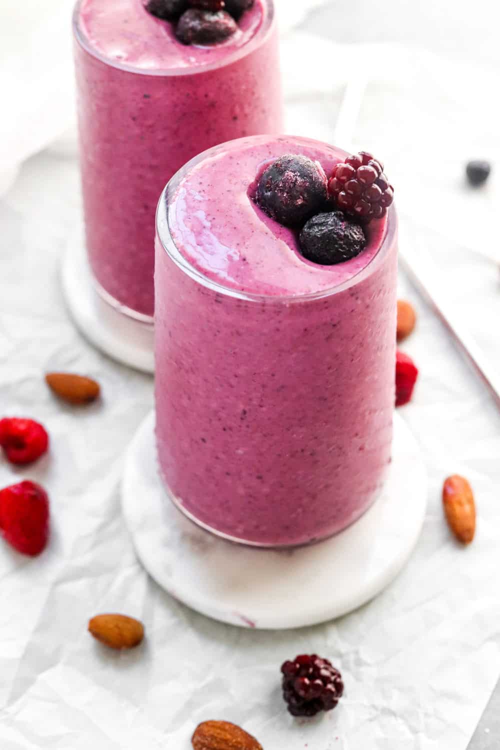 healthy breakfast triple berry smoothie in two glasses with berries on top