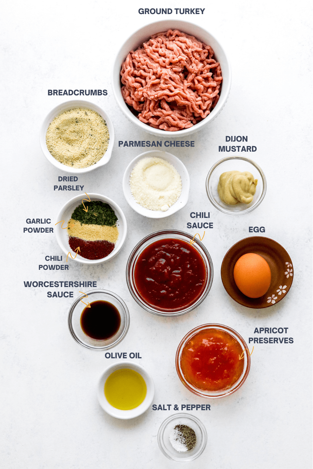Ingredients for turkey meatballs in bowls with labels over each ingredient. 
