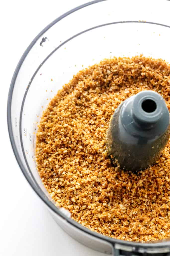 Close up of food processor filled with a crunchy crumble crust