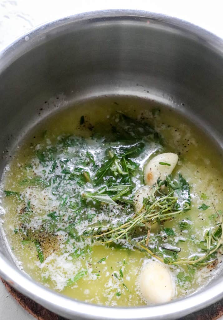 Melted butter and herbs in a silver saucepan