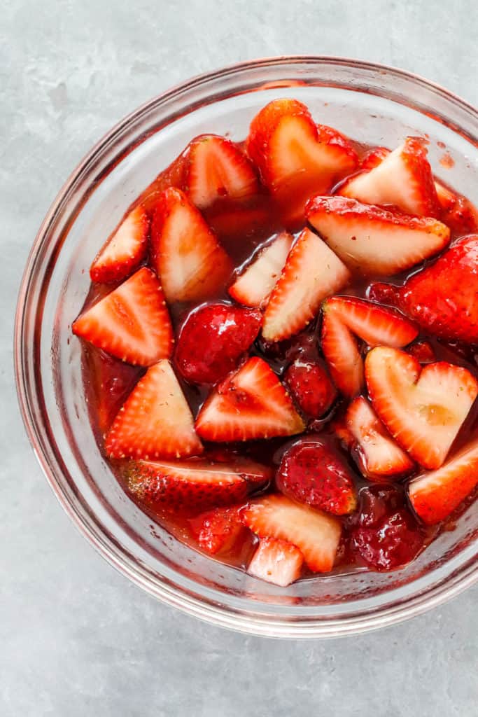 Round glass bowl of sliced glazed strawberries