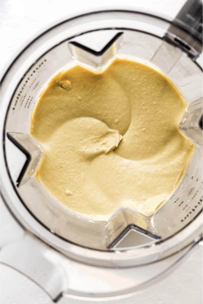 Blender overhead view filled with creamy blended hummus
