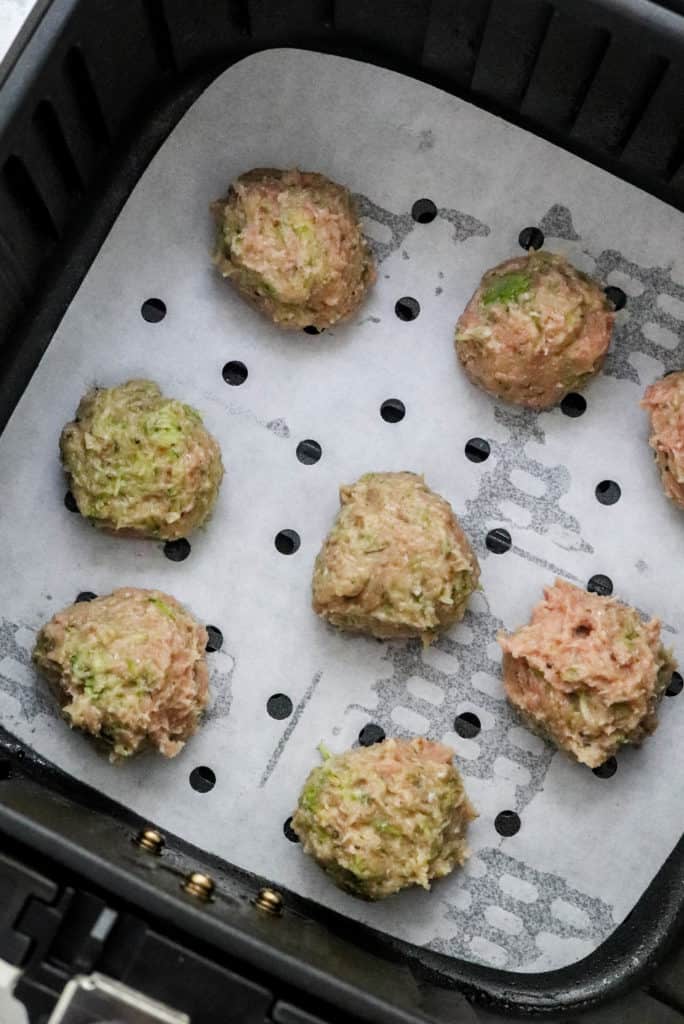 Raw turkey meatballs in a parchment paper lined air fryer basket