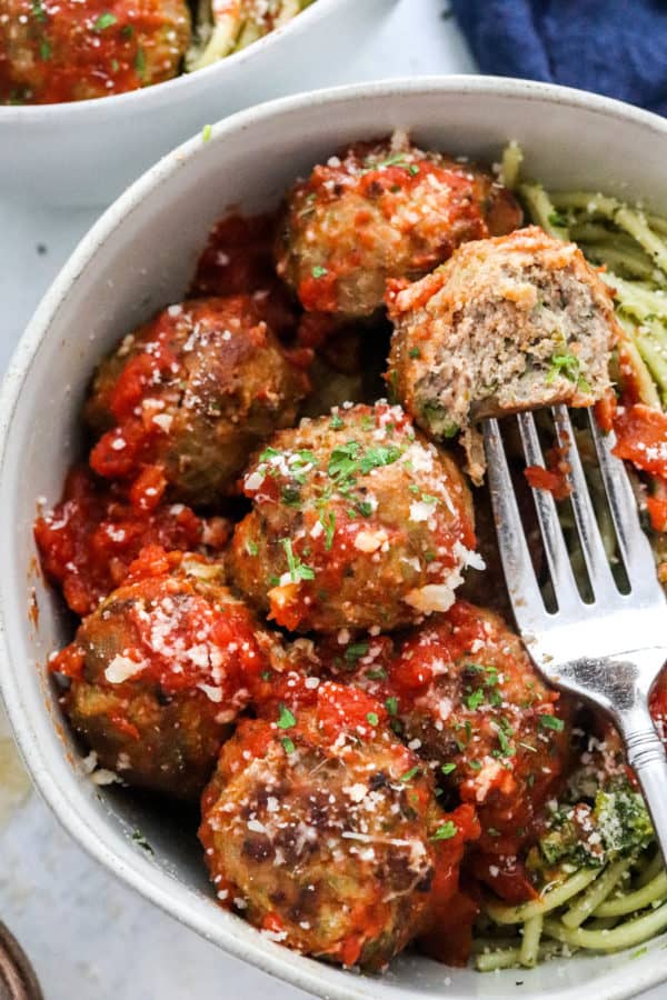 Air Fryer turkey meatballs in around white bow topped with tomato sauce with a fork in one of the meatballs