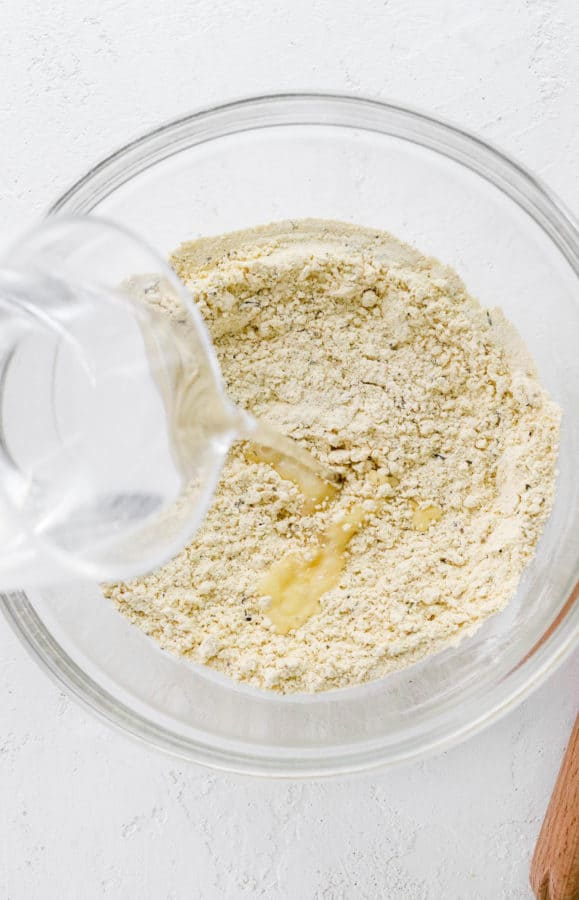 Glass pitcher pouring water into chickpea flour