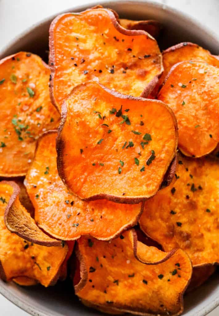 Round sweet potato chips with pepper and parsley on them 