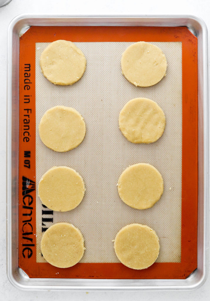 Lined baking sheet with raw round circles cookies on it. 