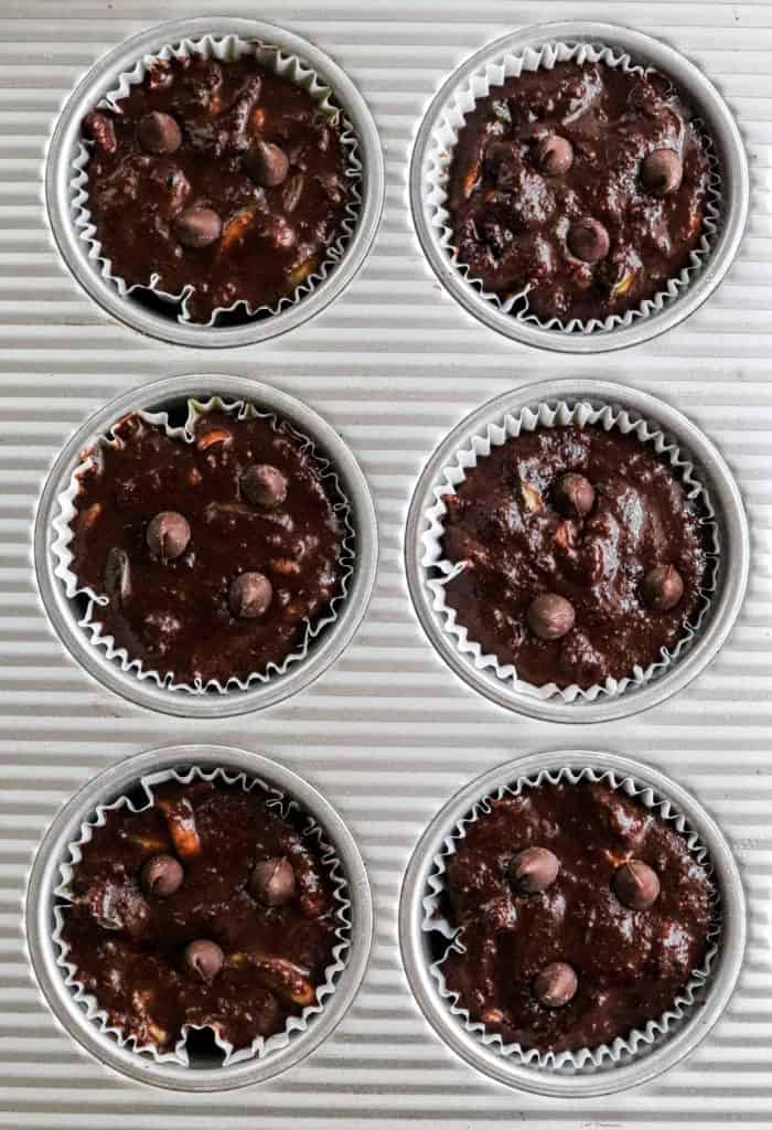 Raw dark chocolate muffin batter in muffin cups in a silver muffin tin