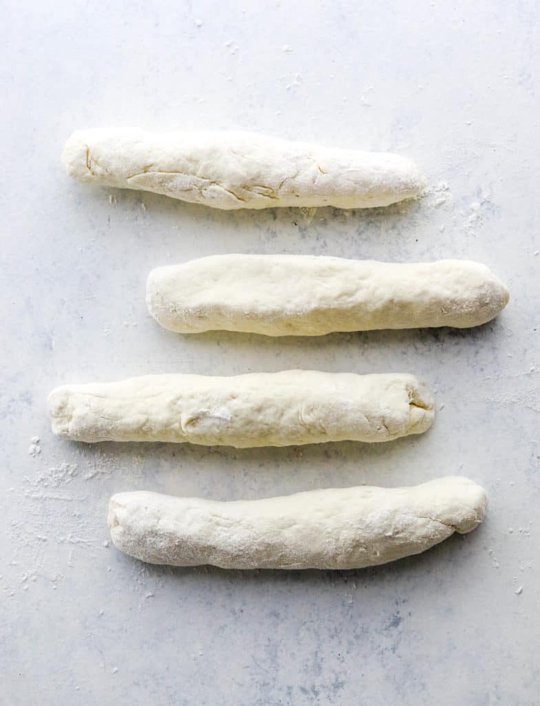 4 long rolled pieces of dough on a white counter. 