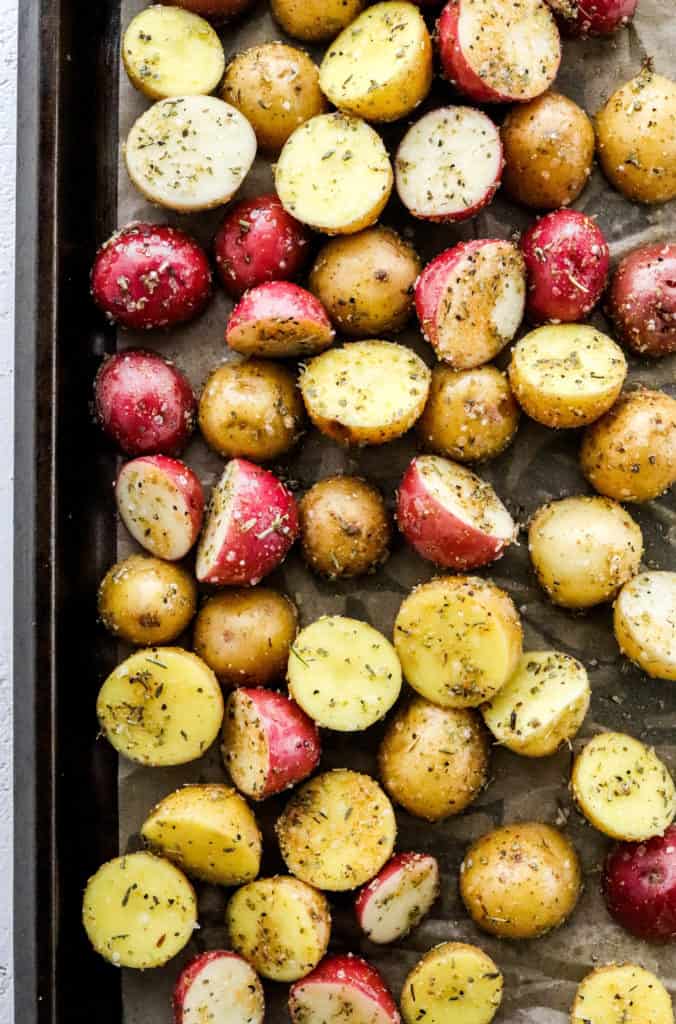 Sliced baby red and yellow potatoes spread onto a dark baking sheet
