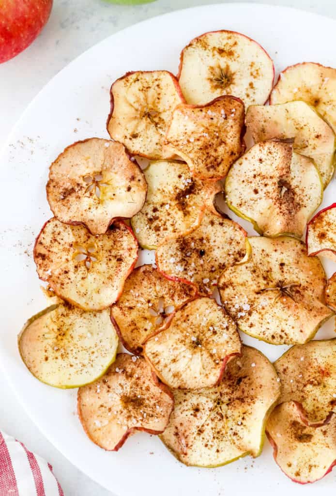 Sliced cooked apples topped with cinnamon on a white round plate