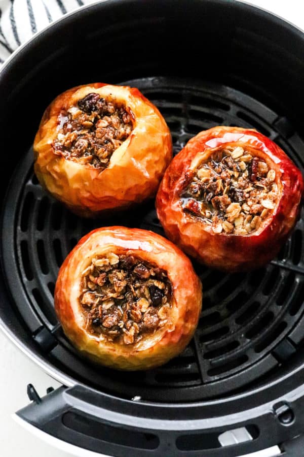 Baked whole apples filled in the center with crumble in a black air fryer basket