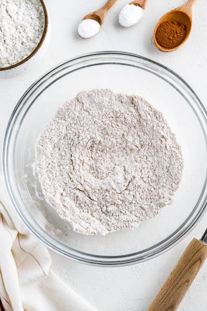 Flour blend in a round glass mixing bowl with bowls of other ingredients around it