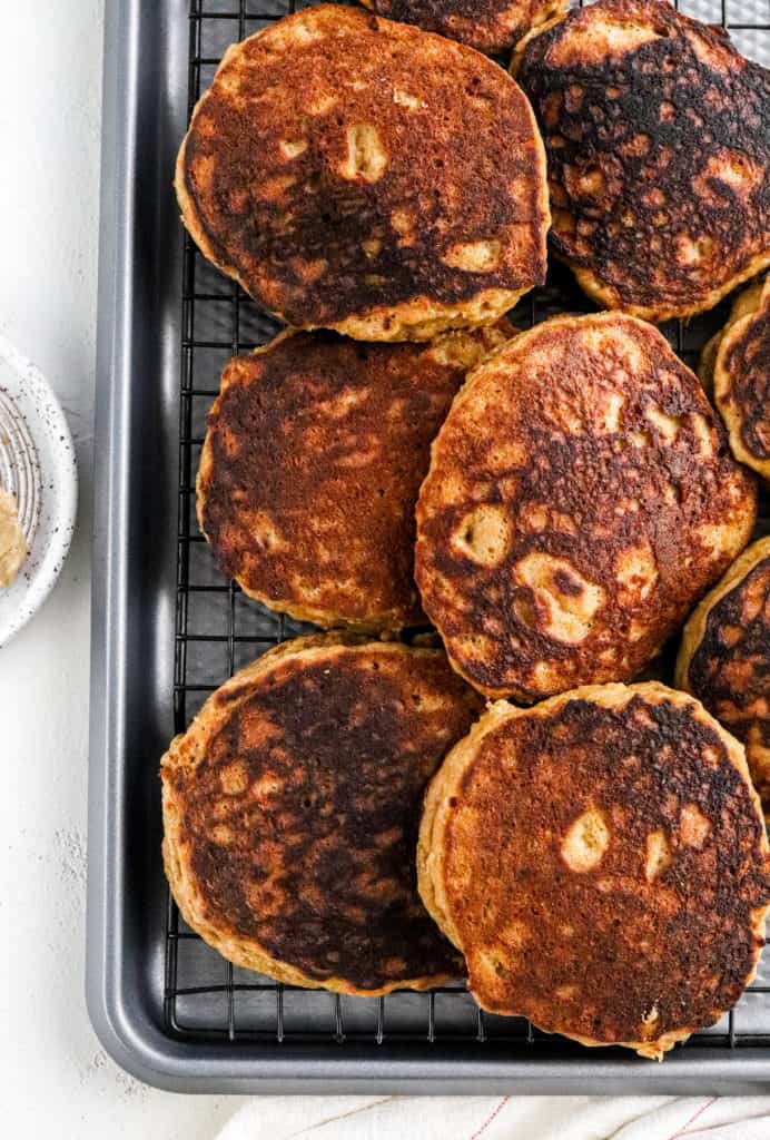 Pile of cooked pancakes on a wire rack on a baking sheet