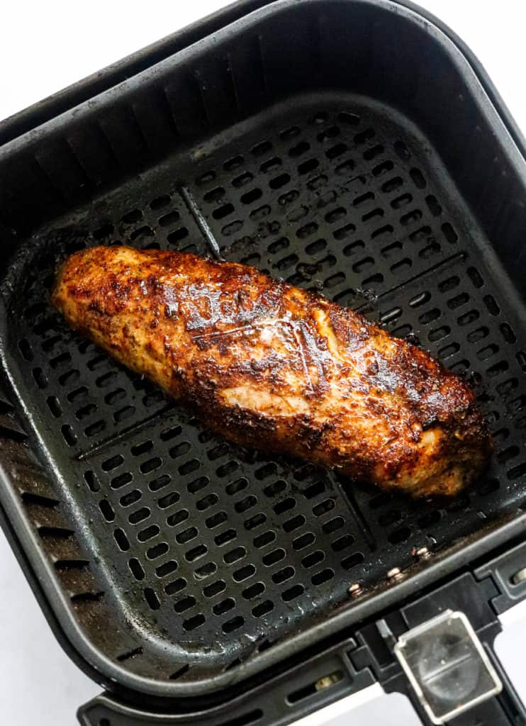 Golden brown, cooked pork tenderloin in a square air fryer basket