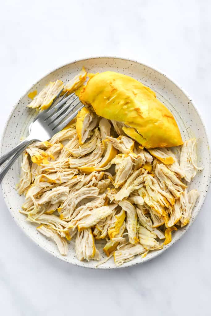 Shredded chicken on a plate with two forks on the plate. 