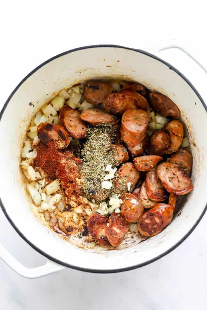 Cooked sliced sausage with herbs and spices in a round, white pot