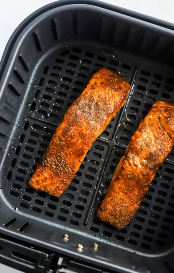 Cooked salmon in a black air fryer basket.