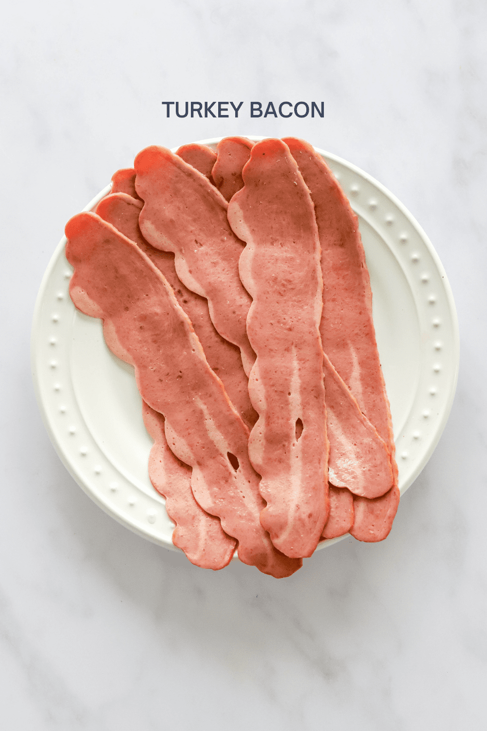 Uncooked turkey bacon on a round white plate. 