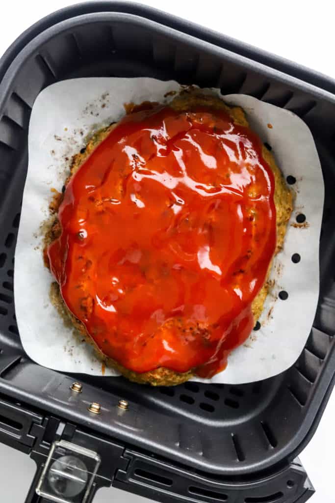 Air fryer meatloaf topped with tomato glaze in an air fryer. 