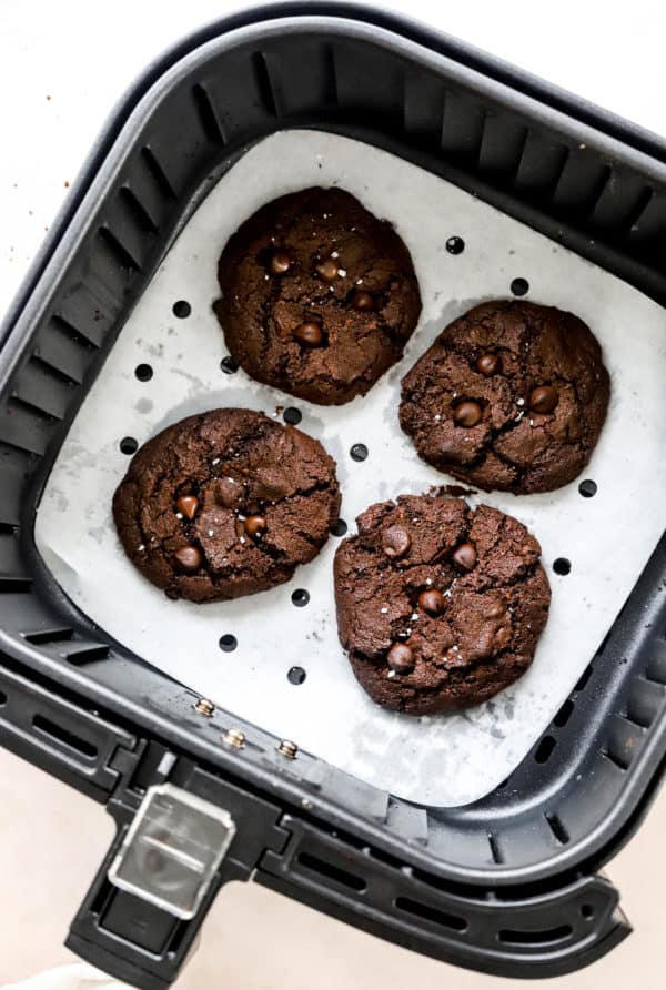 4 chocolate cookies in an air fryer basket.
