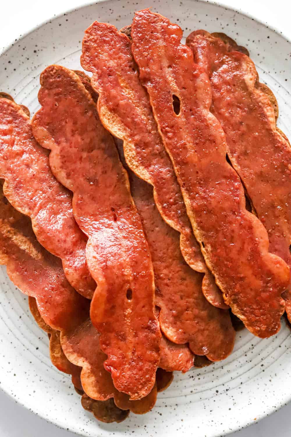 A bunch of cooked bacon on a white plate. 