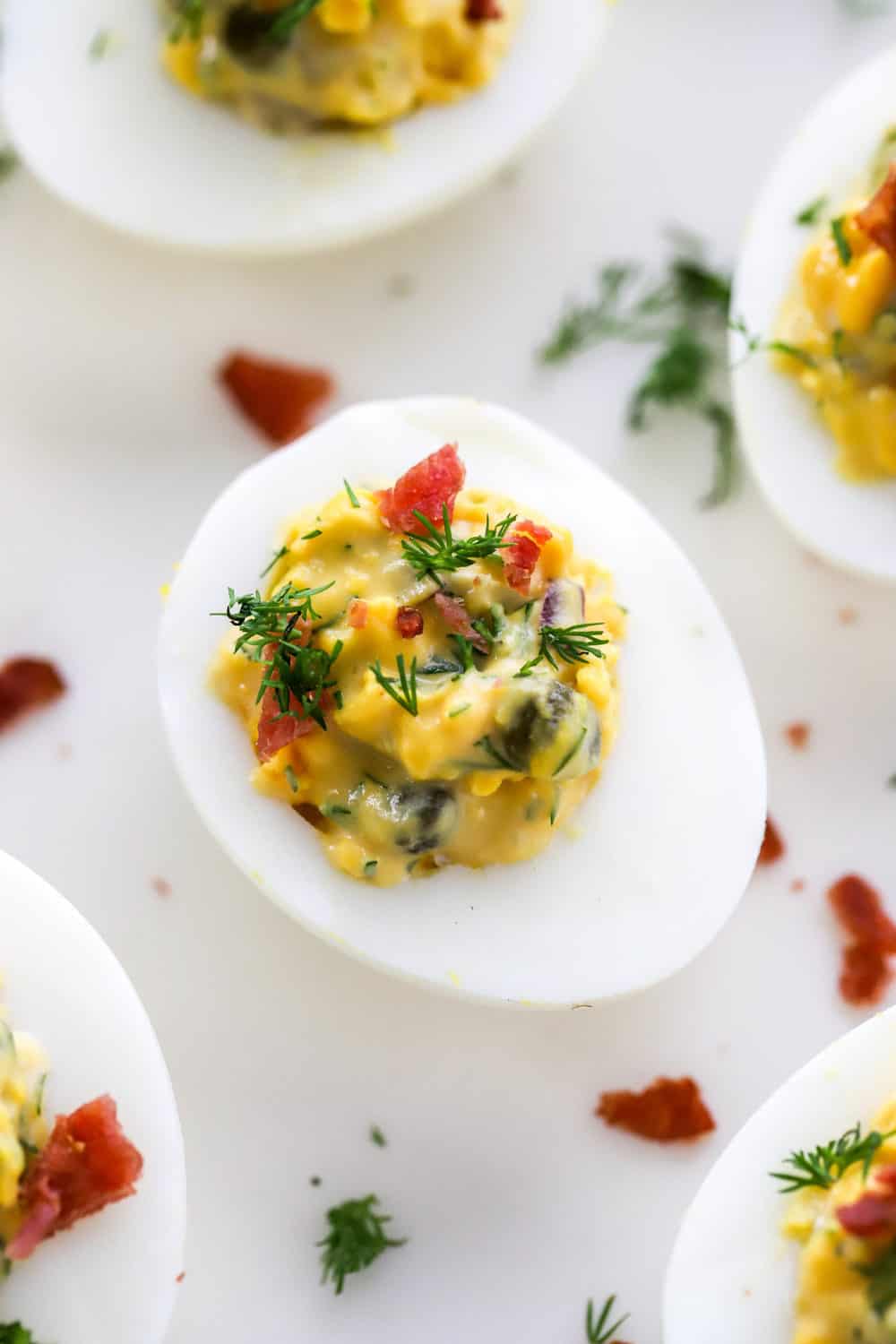 Instant pot deviled egg topped with herbs and bacon with more deviled eggs around it. 