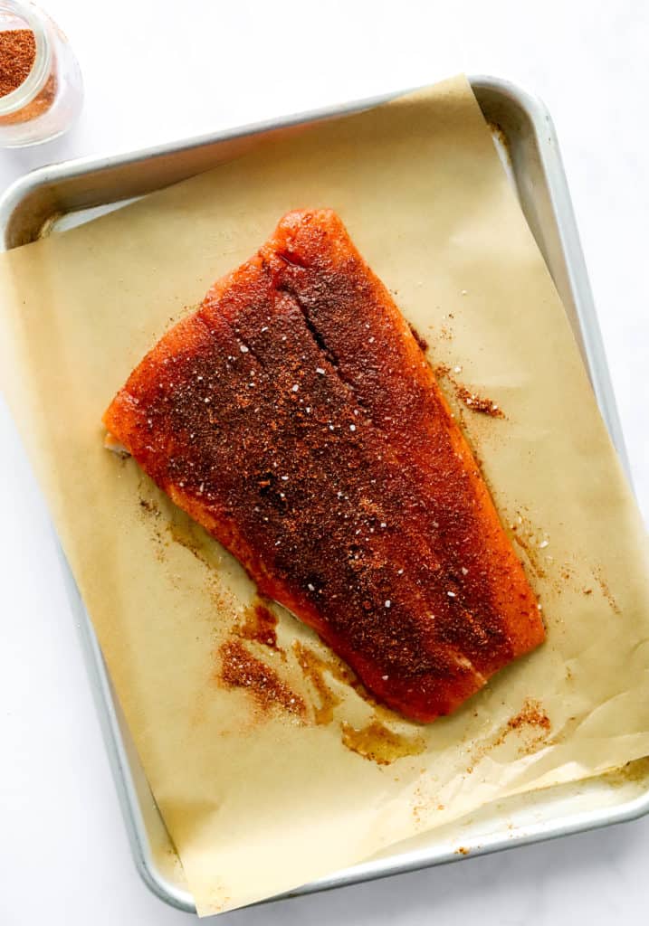 Large piece of salmon on brown parchment paper on a baking sheet. 