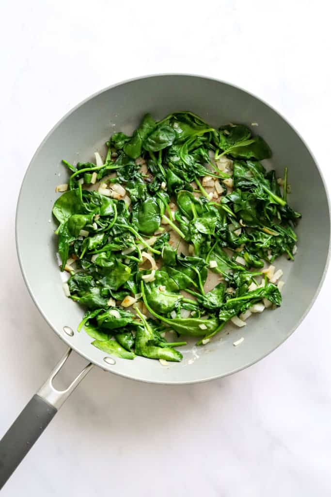 Sautéed spinach and onions in a pan. 