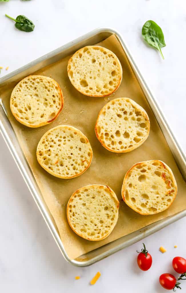 6 toasted English muffins on a baking sheet. 