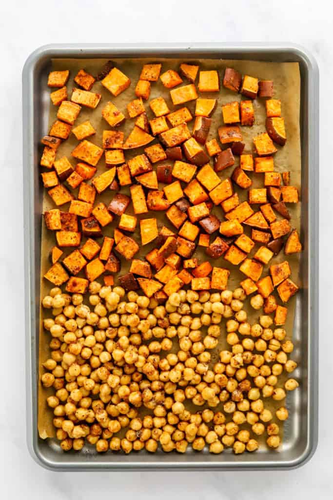 Roasted, diced sweet potatoes and chickpeas on a baking sheet. 