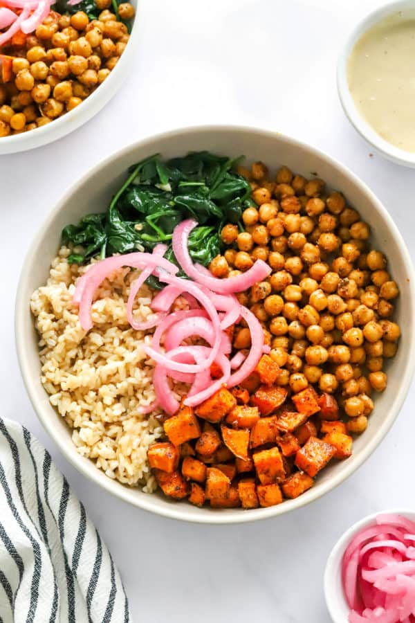 Roasted chickpeas, sweet potato, sautéed spinach and brown rice in a bowl.