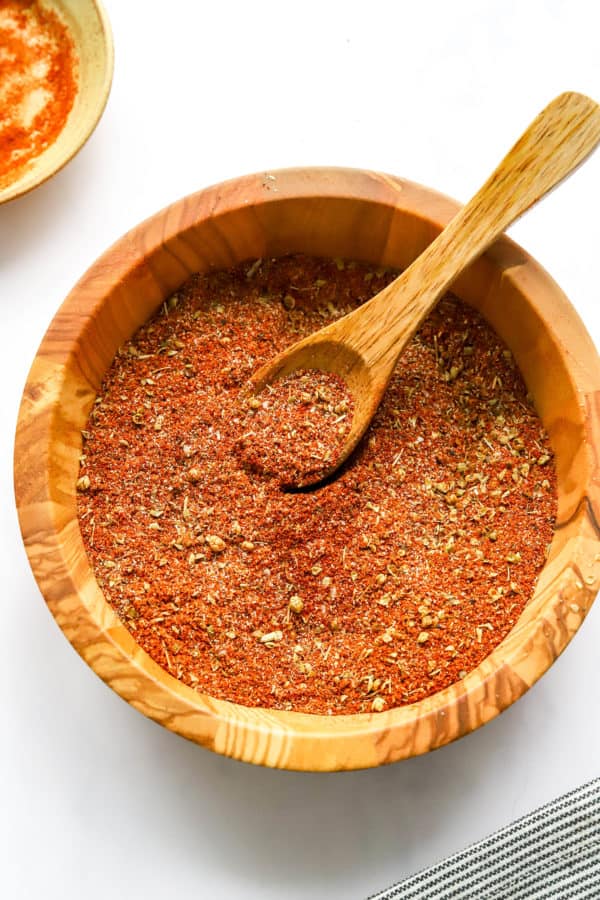 Cajun Seasoning mixed up in a brown bowl with a wooden spoon in the bowl.