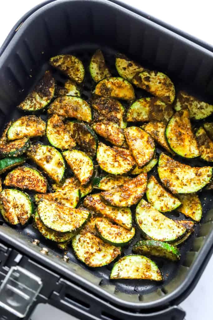 Cooked, sliced Zucchini in a black air fryer basket. 